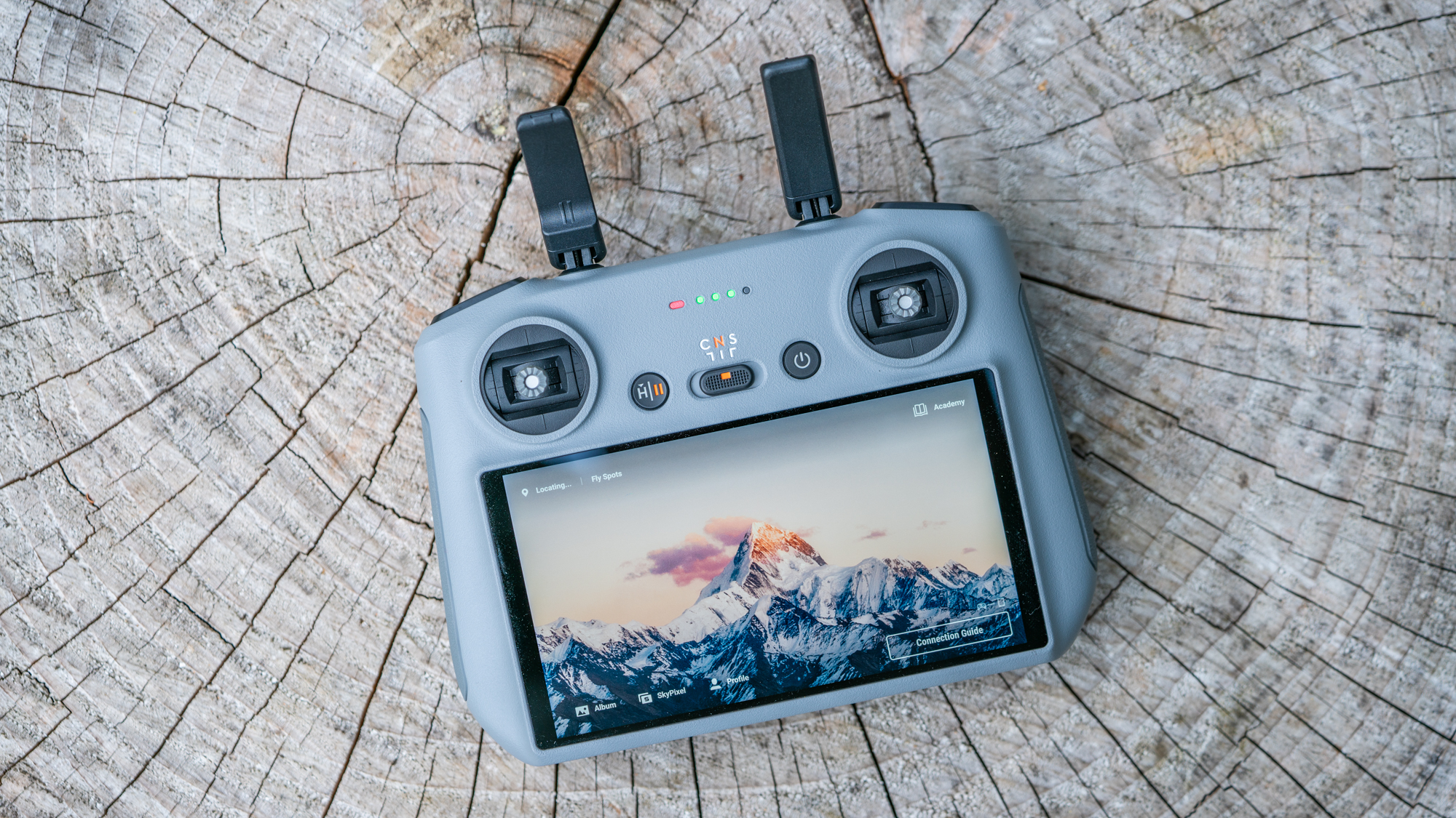 DJI Air 3 drone remote controller with built-in screen, on a tree stump