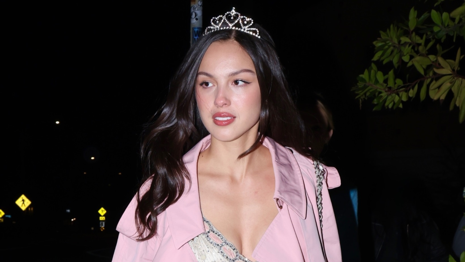 Olivia Rodrigo is pretty in pink on her birthday, pairing a tiara with a Barbie pink duster coat, a glittery dress, and bubblegum pink mules