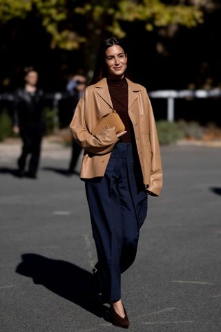 woman wearing leather blazer, black top, heels, and navy pants