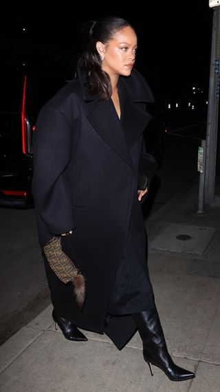 Rihanna wears a long black coat, black leather boots, and carried a vintage Fendi bag