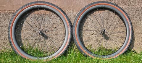 Two Parcours Alta 650B gravel wheels fitted with Hutchinson Touareg tyres, leaning against a wall on some grass
