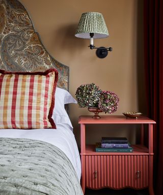 Bedroom with caramel color wall, red nightstand and luxury bed