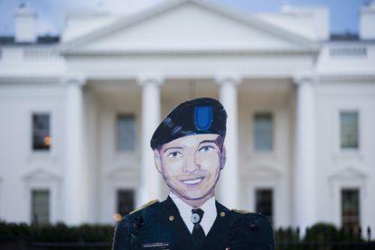 A poster of Chelsea Manning's face in front of the White House