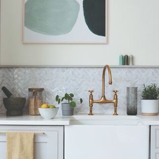 A kitchen with a tiled splashback and an artwork