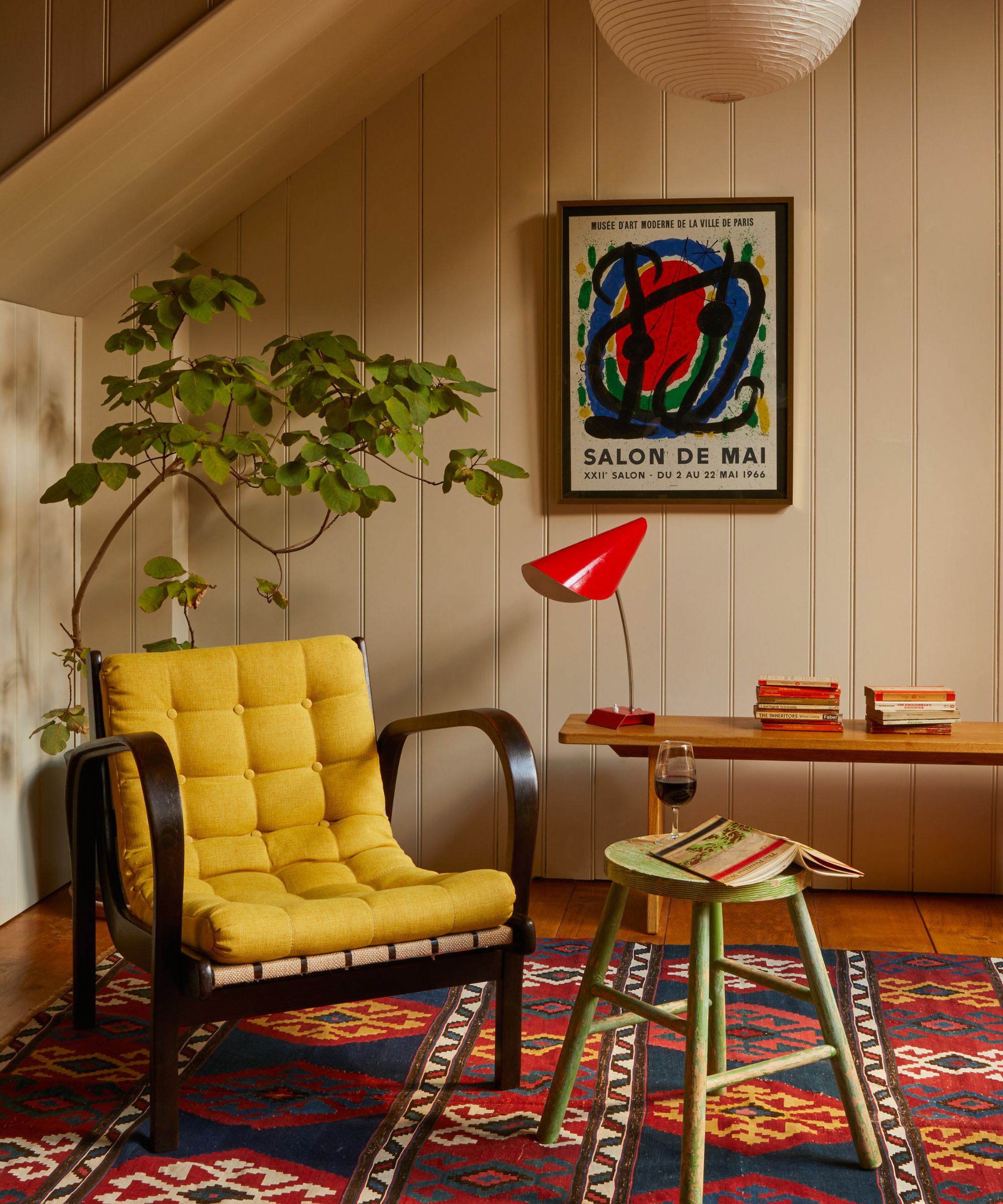 A home office with paneled walls and an antique armchair upholstered in bold yellow fabric