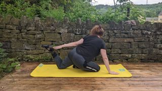 Samantha Priestley holding a yoga stretch, part of doing yoga every day, on mat in backyard
