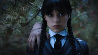 A close up of Wednesday Addams, with Thing standing on her shoulder, in Wednesday's Netflix TV series