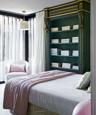 Bedroom with green antique bookcase and pink bed sheets