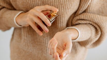 Woman spraying perfume on wrist