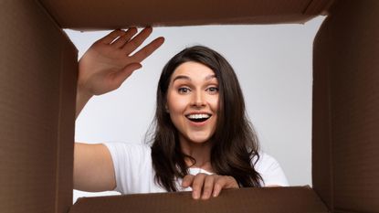 A woman looks inside a box and smiles.