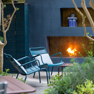 Blue aluminium chairs sat in a modern garden beside a firepit