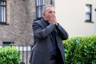 EastEnders David Wicks standing in the Square with his hands to his face in shock