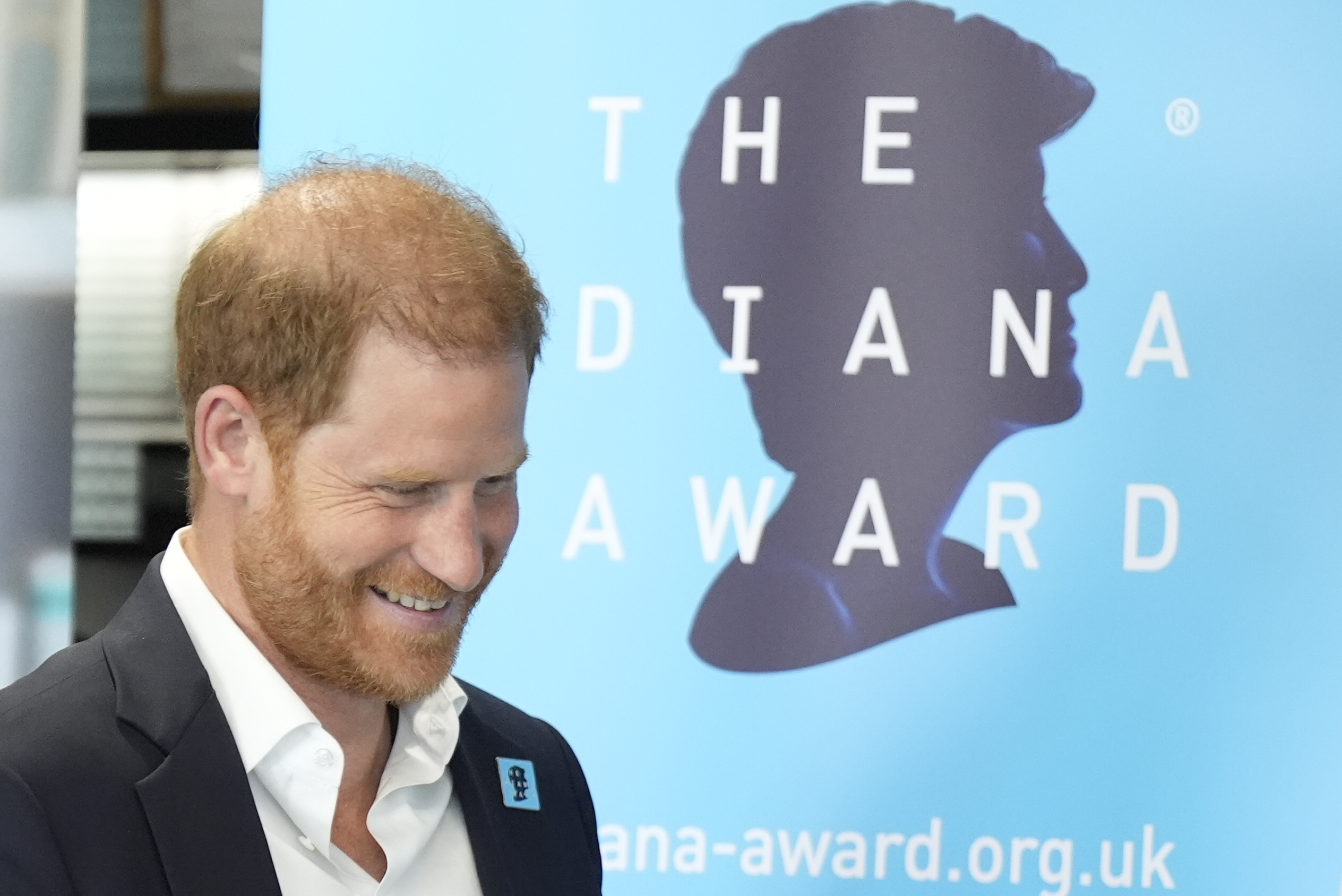 Prince Harry standing in front of a Diana Award sign