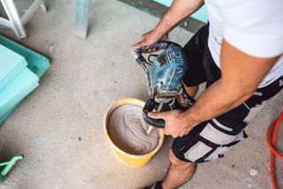 Mixing up plaster in a pot with a powertool