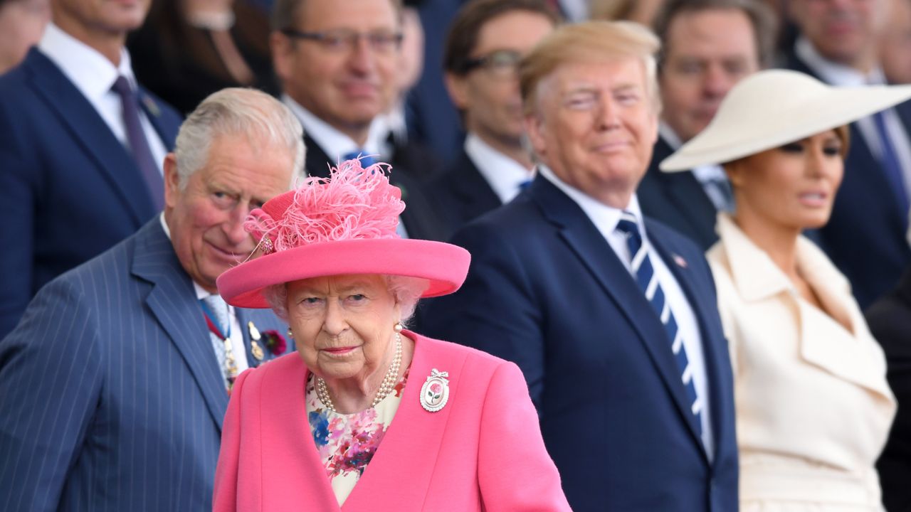 Queen Elizabeth wearing a pink coat and hat walking away from Donald Trump and Melania Trump