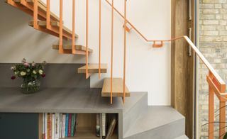 Steel and oak staircase cantilevers over the kitchen