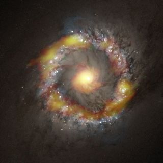 The distribution of two gases, hydrogen cyanide (red) and formyl cation (green), are shown overlaid on an image of the galaxy NGC 1097 taken by the Hubble Space Telescope.