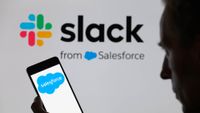 Salesforce logo is being displayed on a smartphone, with the Slack logo in the background