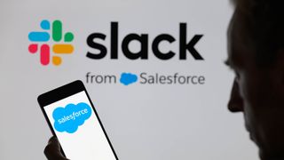 Salesforce logo is being displayed on a smartphone, with the Slack logo in the background