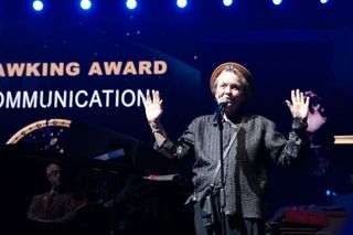 a person in a suit receives an award onstage