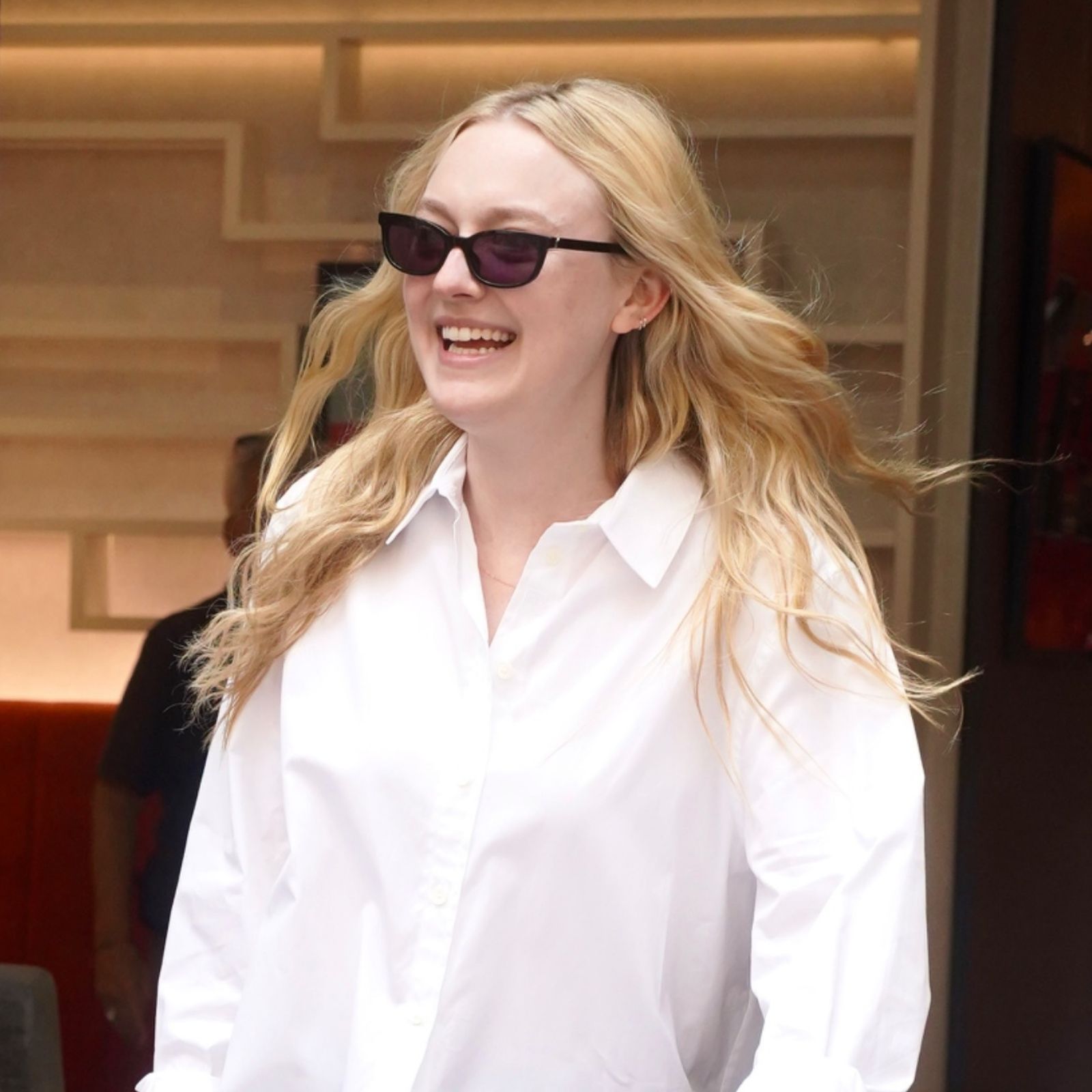 Dakota Fanning wears black ballet flats with a white Oxford shirt and sunglasses in Paris. 