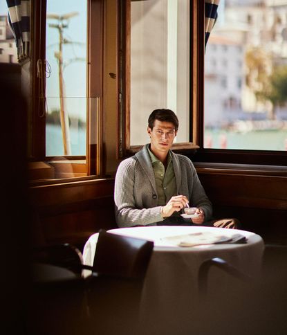 Male wearing knitted cardigan drinking coffee