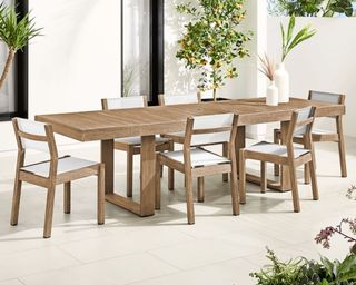 A wooden outdoor dining table and six dining chairs on a paved patio