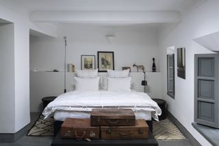 white bedroom decor with leather trunks and artworks