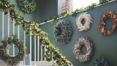 Olive green hallway covered in natural wreaths