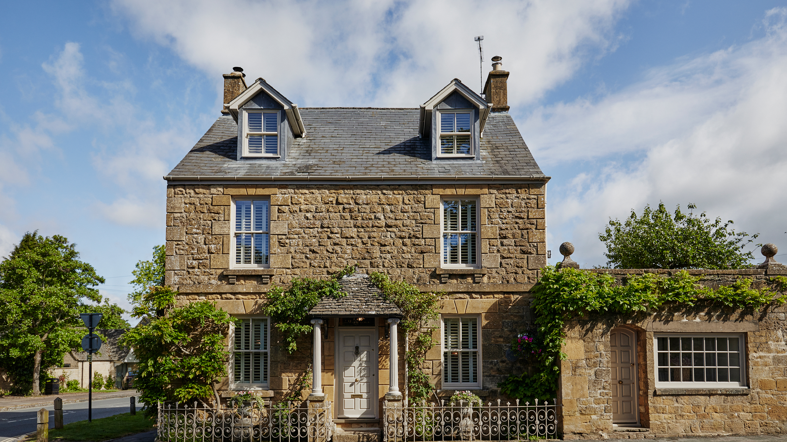exterior of a cotswold stone townhouse with front portico and dormer windows