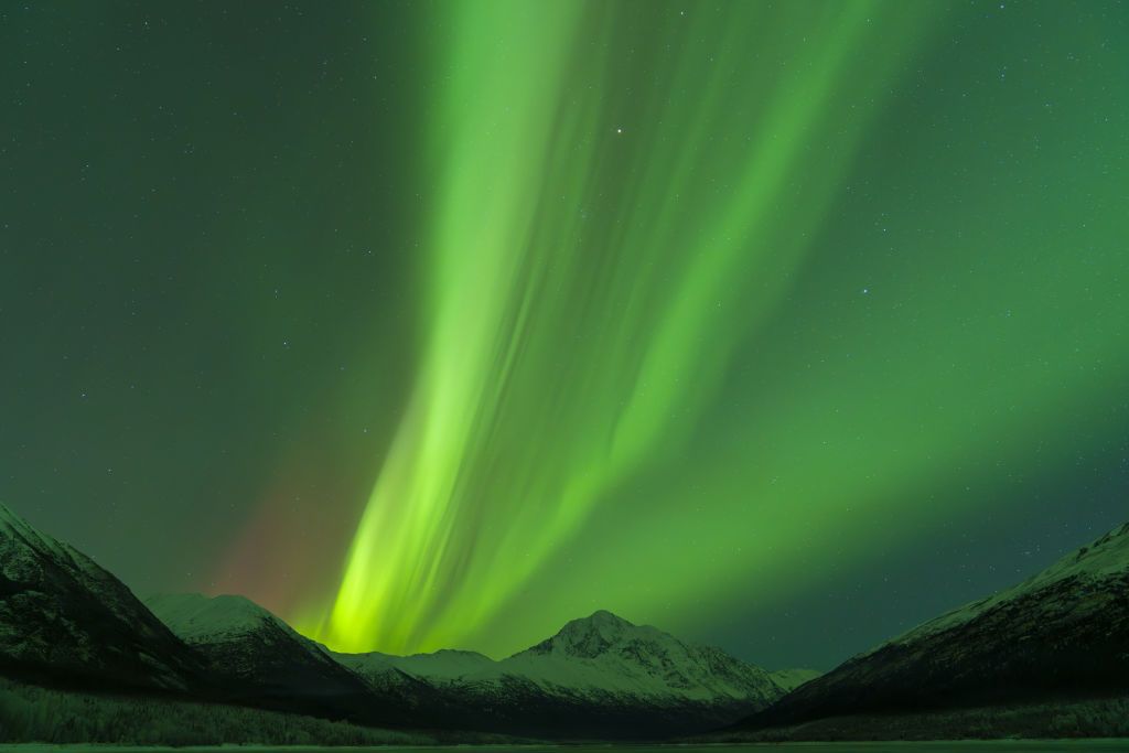 northern lights above alaska during new year's celebrations. large ribbons of green light dance through the sky.