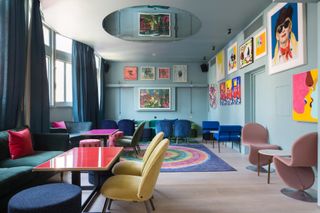 Alternative view of Groucho Club's inner space featuring colourful art, tables, chairs and a mirror on the ceiling