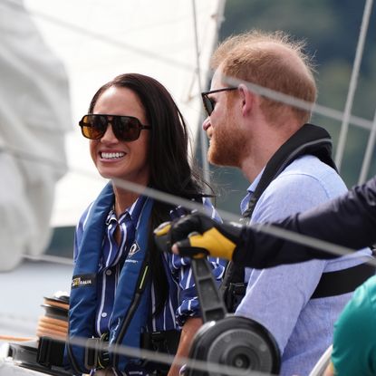 Meghan Markle and Prince Harry sitting in a boat wearing life vests and sunglasses