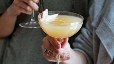 Hands holding cocktails with a slice of pear in