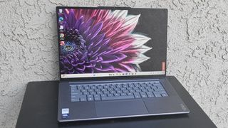 Lenovo Yoga Slim 7i Aura Edition powered on resting on a small black table outside