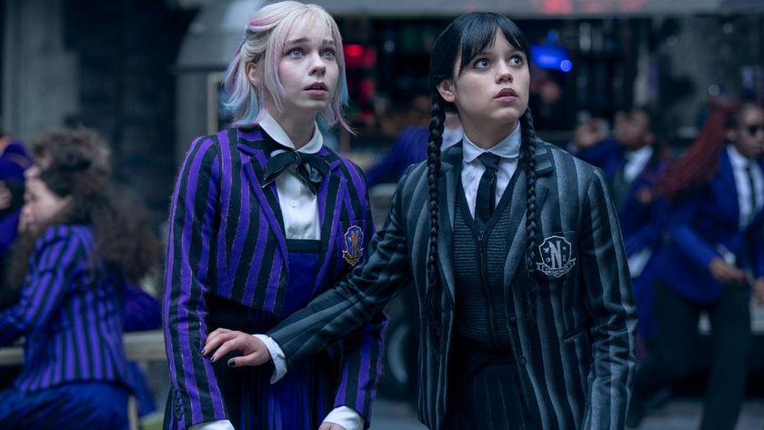 From left to right: Emma Myers as Enid looking up and scared and Jenna Ortega as Wednesday holding her left arm in front of Enid and looking up scared. 