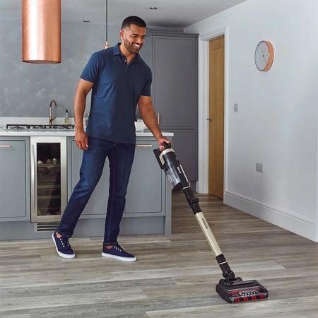 A person using a Shark cordless vacuum on a wooden floor