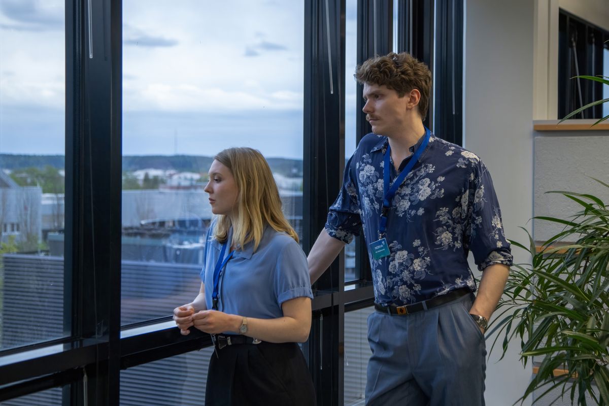 An image from Mobile 101 showing Katarina (Satu Tuuli Karhu) and Aki (Emil Kihlström) inside an office looking out of the window