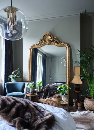 Grey bedroom with large leaning gold mirror