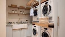 laundry room with two dryers and two washers. marble trims, and pull out clothes racks