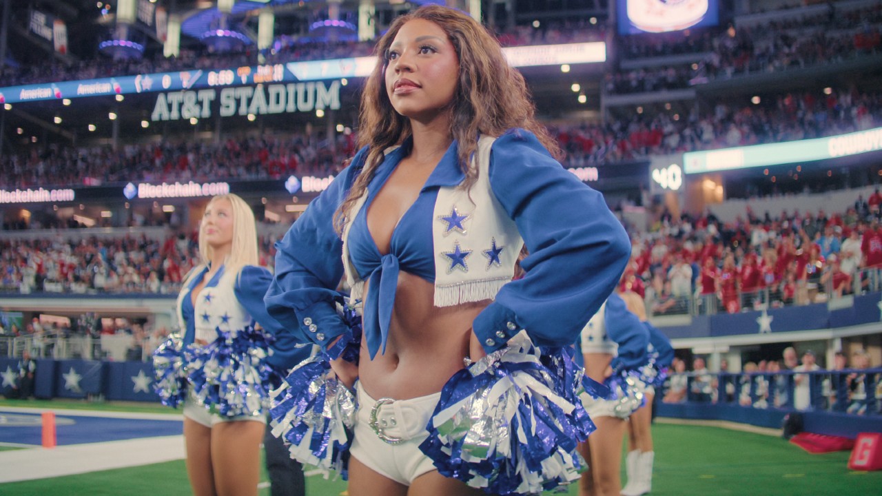 Armani in America's Sweethearts standing in her Dallas Cowboys uniform holding her pom poms with her hands on her hips.