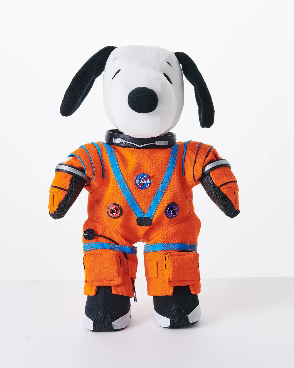 Um boneco de pelúcia Snoopy usando o clássico traje laranja e azul dos astronautas da NASA