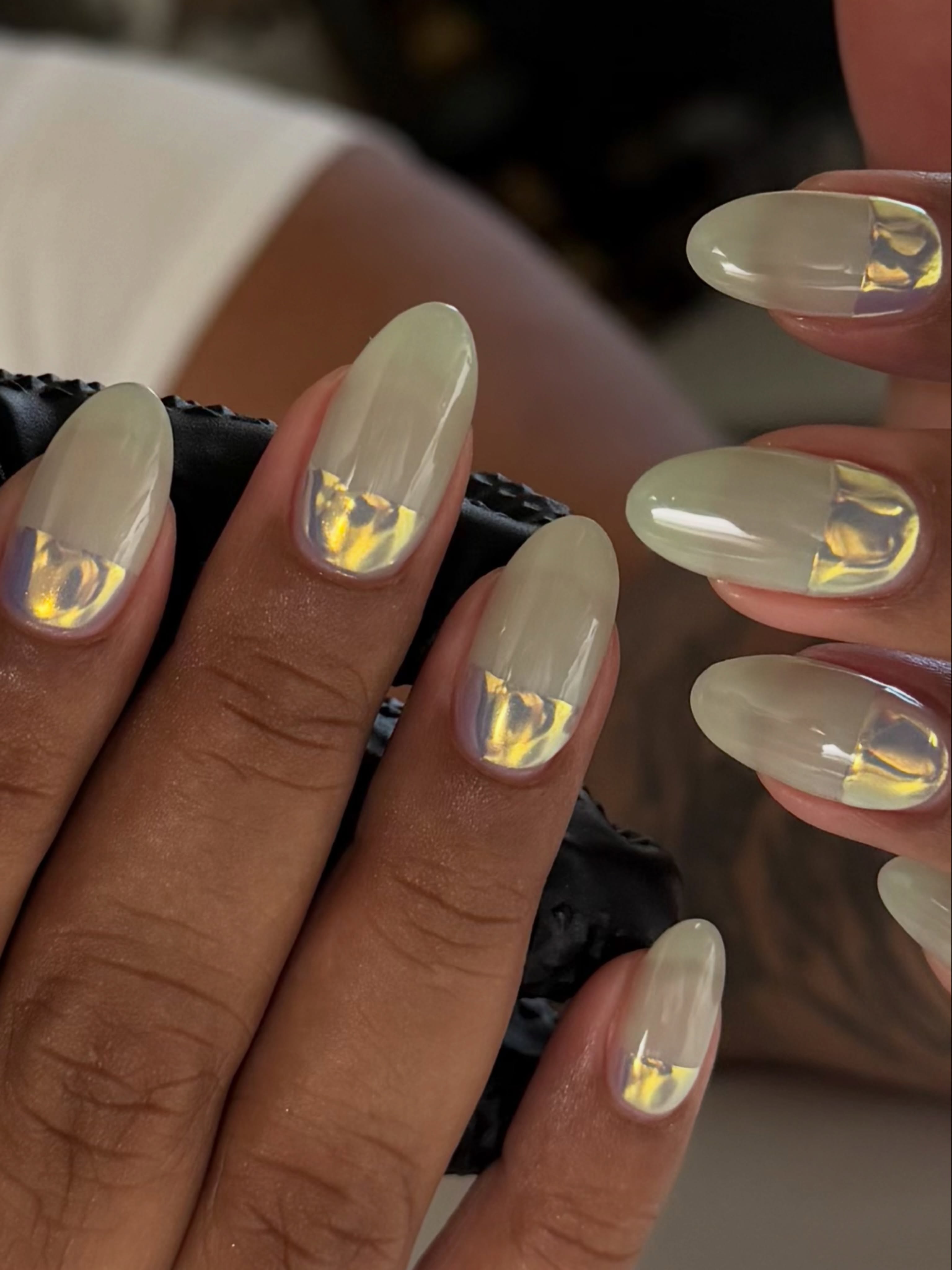 Sage almond nails with flashes of iridescent yellow, lavender and silver foil along the bottom