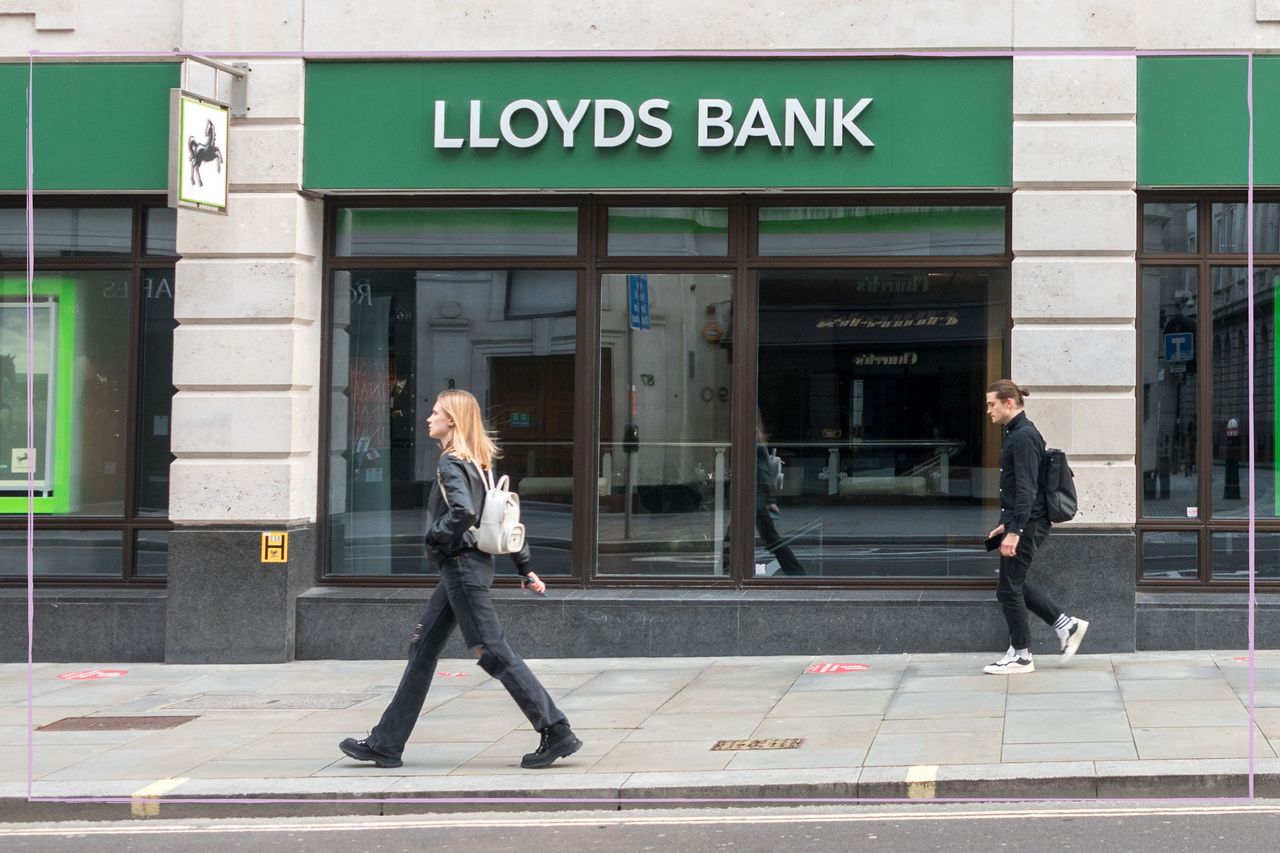 a long shot showing a blonde womna walking past the front of a Lloyd&#039;s bank branch