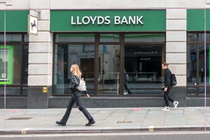 a long shot showing a blonde womna walking past the front of a Lloyd's bank branch