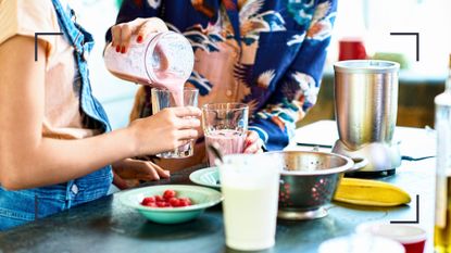 Two women making detox drinks to lose weight in a blender in the kitchen