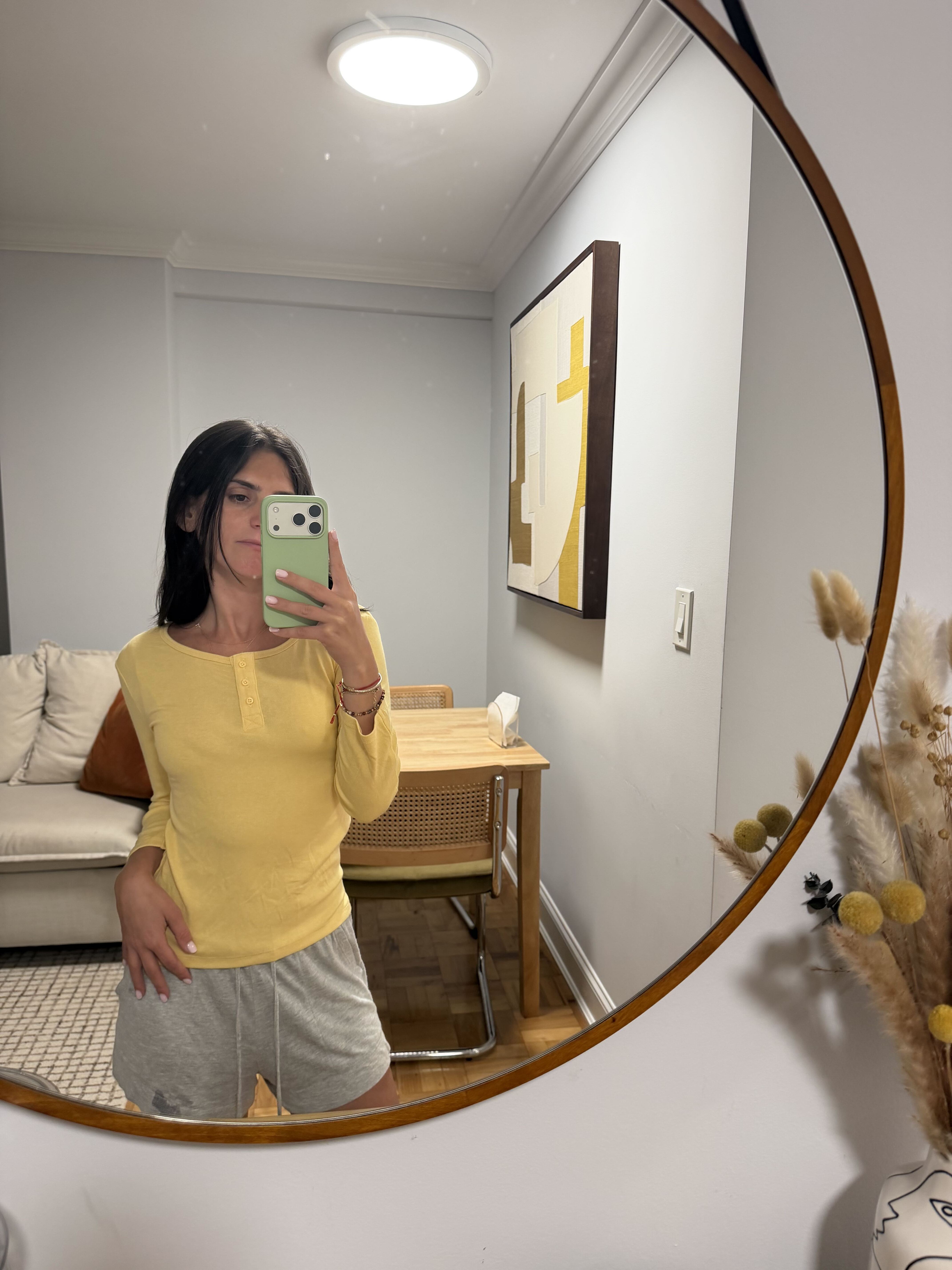 ari wears a yellow henley tee and a gray shorts.