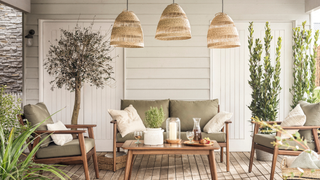 Garden area with sofa, olive trees, rattan lights and wooden decking under a cover