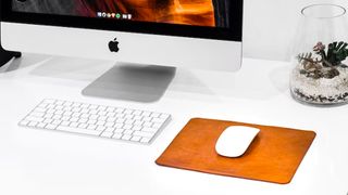 A shot of the Apple Magic Mouse with a keyboard and Apple Mac on a desk