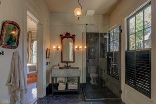 A modern gothic bathroom with sconce lights flanking a mirror, black marble tiles and large rectangular sink